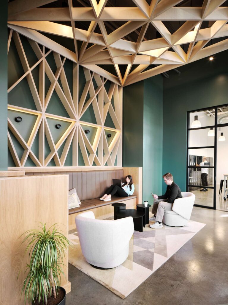 550 MLK in Portland, OR features a modern lounge area with custom lighting and electrical work. The space includes a geometric wood wall, built-in bench, and glass door leading to a mixed-use real estate office. Electrician services ensured safe and functional electrical installations throughout the area.