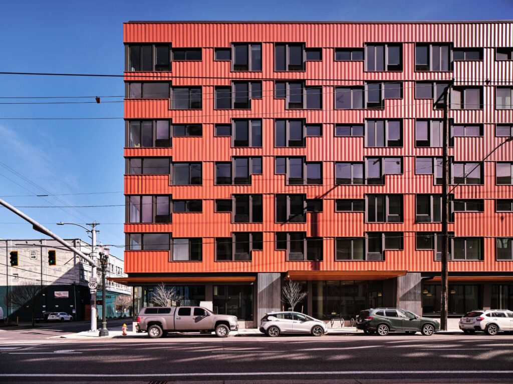Located at 550 MLK in Portland, OR, this modern mixed-use apartment building features large windows and is situated along a city street with overhead utility lines—ideal for those seeking professional electrician services.
