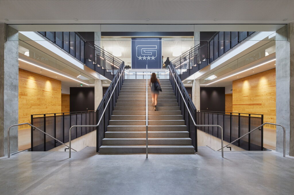 An electrician in Vancouver, WA can enhance modern buildings like Grant High School by expertly installing and maintaining overhead lighting, ensuring safety and functionality, amidst concrete floors and wooden wall panels.