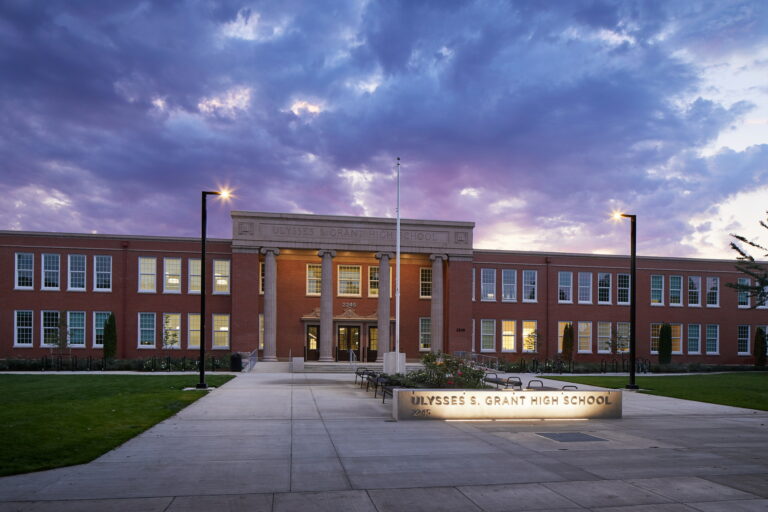 Grant High School in Portland, OR, features a prominent brick facade with illuminated signage, perfect for showcasing electrical work. The well-lit pathways and entrance highlight the importance of reliable electrician services to ensure safety and visibility.