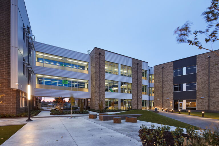 Located in Vancouver, WA, this modern three-story building offers comprehensive electrician services. The brick and metal exterior is complemented by large windows, and the surrounding landscaped paths are well-lit with outdoor lights, ensuring safety and visibility during early evening or dusk.