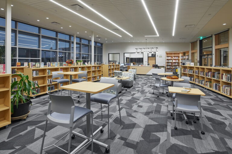 Located in Vancouver, WA, this modern library features a well-lit space with large windows, wooden bookshelves, and geometric-patterned carpet. The inviting high school library includes designated areas for reading and studying. If you need electrician services to optimize lighting or ensure electrical safety in public spaces like these, reach out to local professionals for assistance.