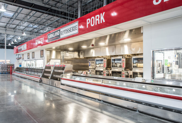 In a commercial kitchen setup reminiscent of a warehouse, the emphasis on deli meats, poultry, and pork is supported by stainless steel equipment and counters. Located in Vancouver, WA, our electrician services ensure optimal lighting with well-maintained fluorescent fixtures to highlight different sections efficiently.
