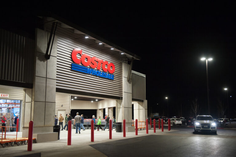The image shows the well-lit entrance of a Costco Wholesale warehouse at night in Bellingham, with people entering and exiting. If you're in need of electrician services in Vancouver, WA to enhance your property's lighting like this, we can help!.