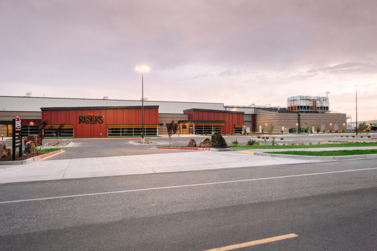 Reser Fine Foods features a spacious parking lot and modern building with red and gray panels.