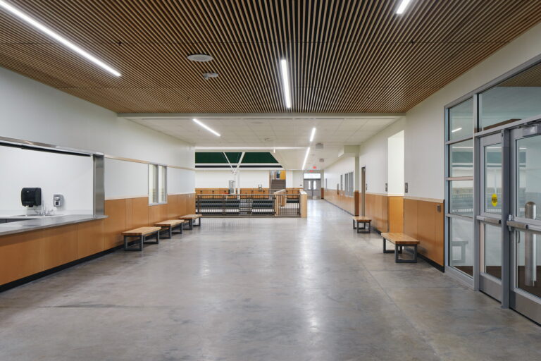 The hallway at Tigard High School features recessed lighting set in a wooden-slat ceiling, installed by professional electricians. If you're in Vancouver, WA, and need similar expert electrician services for lighting installations or upgrades, contact us today.