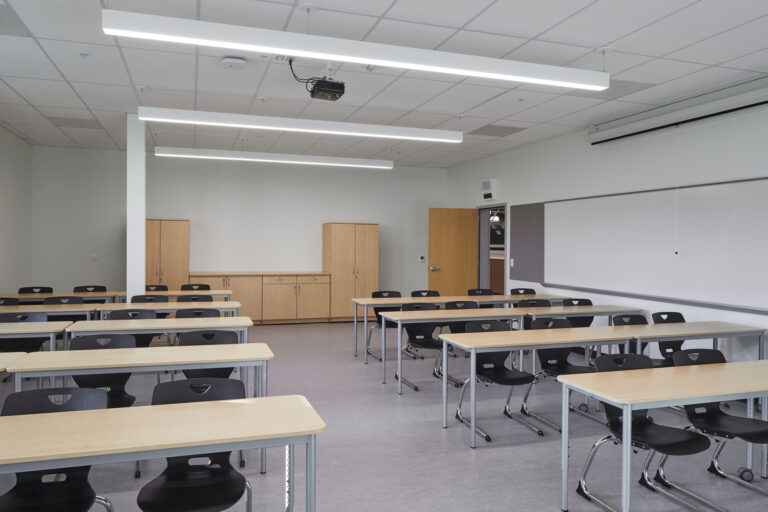A modern classroom at Tigard High School is well-equipped with necessary electrical features. Ceiling lights and a projector ensure proper illumination for learning activities.