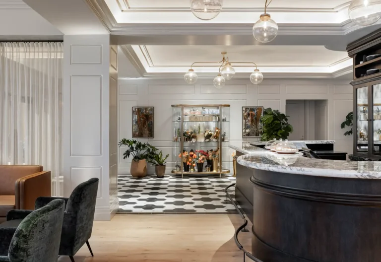 A modern lobby area with a curved reception desk, patterned floor tiles, and a display case with decorative items. The space is well-lit with pendant lights installed by an electrician in Vancouver, WA, and has seating areas with green and brown chairs.