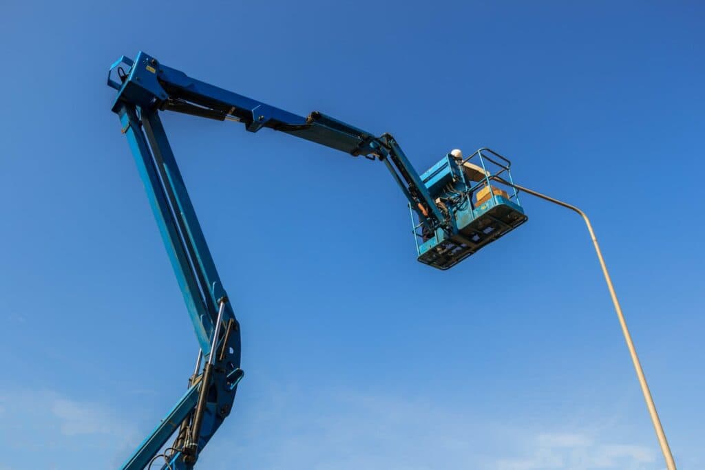 An electrician works high up on a crane to fix a street light to illustrate All About Electricians Past, Present, and (Your) Future