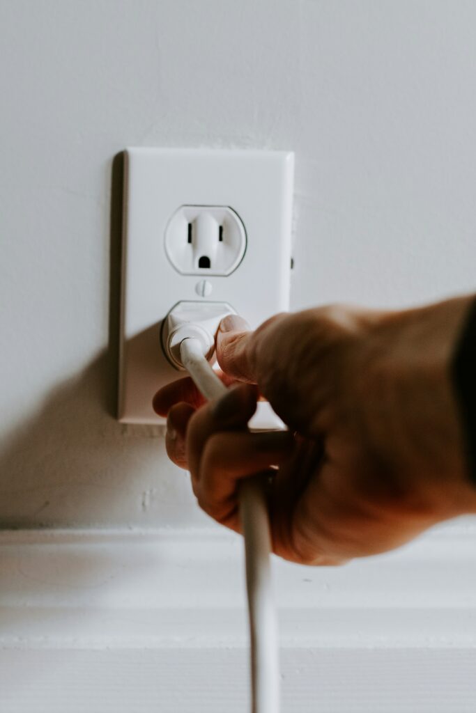 An electrician in Vancouver, WA plugging a cord into a residential electrical outlet.