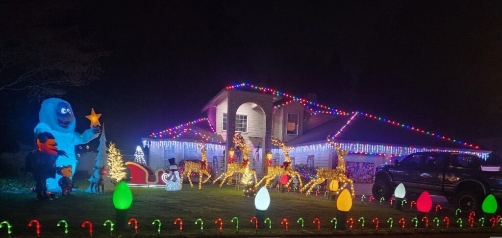 Vancouver, WA house with pro-installed colorful Christmas lights, inflatables, and yard decor—expert electrician services featured.