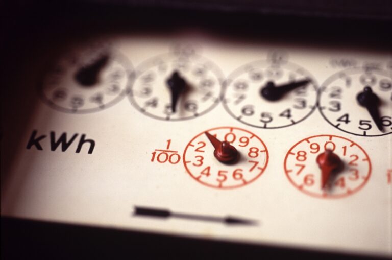 Close-up of an analog electricity meter displaying kilowatt-hour (kWh) usage with black numeric dials and one red dial indicating precise measurements.
