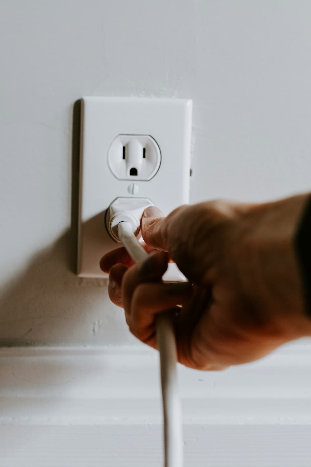 A local electrician in Vancouver, WA is seen plugging a cord into a wall outlet.