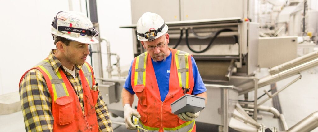 An electrician, donned in a hard hat and vest, is seen carrying a box in Vancouver, WA.