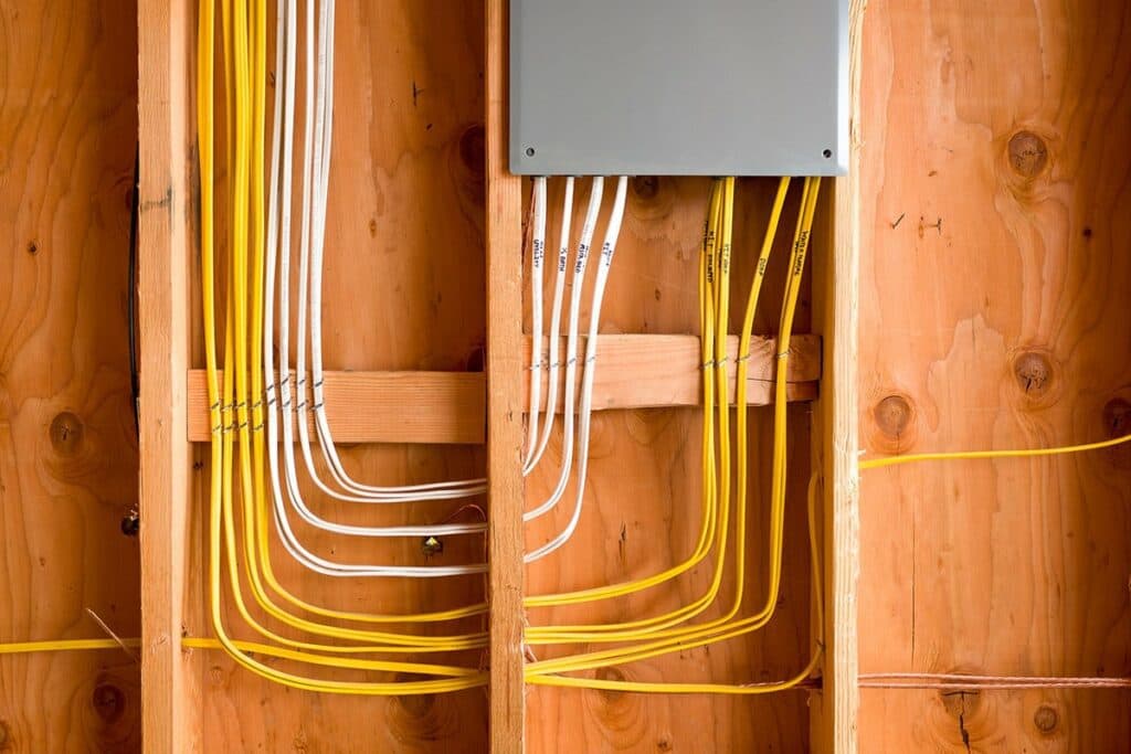 A local electrician in Vancouver, WA is handling residential electrical wiring in a house with yellow wires. This electrician is skilled at ensuring all electrical systems are safely and efficiently installed.