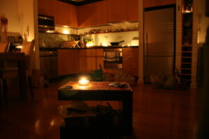 Power outage in a Vancouver, WA home; only a candle lights the room. Kitchen appliances and bags are visible in the dark.
