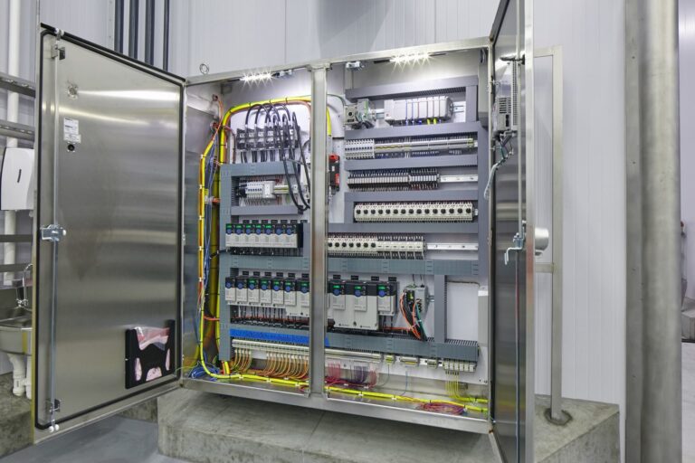 An open industrial electrical control panel, meticulously arranged with various wires, circuit breakers, and components inside a metal cabinet, showcases the precision of an electrician in Vancouver WA.