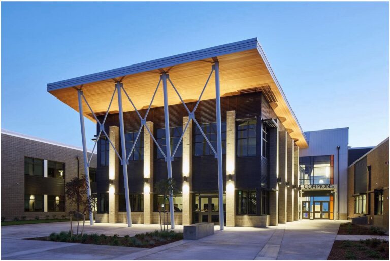 A modern two-story building with large windows, a wooden overhang, and tall support columns. The entrance is lit by the skilled work of a Vancouver electrician and marked "Commons.
