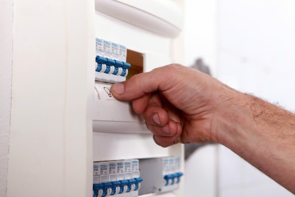 In Vancouver, WA, a local electrician's hand is grasping a switch inside of an off-white electrical box.