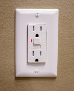 GFCI outlet with two sockets, reset and test buttons, on beige wall in Vancouver, WA. Installed securely for electrical safety.