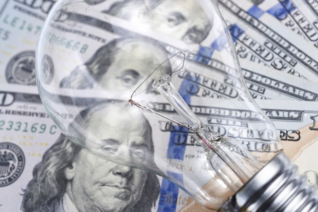 Light bulb over dollar bills to illustrate Troubleshooting A High Electric Bill